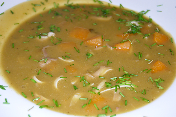 Erbsensuppe mit Schweineohr und Steckrüben, mit Schnittlauch garniert