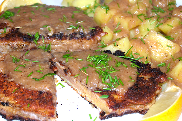 Panierte Kuheuterschnitzel mit Salzkartoffeln, mit Meerrettichsauce und kleingeschnittenem Schnittlauch garniert