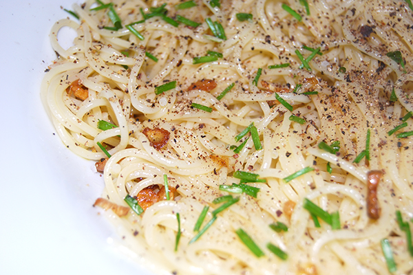 Spaghettini aglio e olio, im tiefen Nudelteller angerichtet, mit Salz, Pfeffer und Schnittlauch