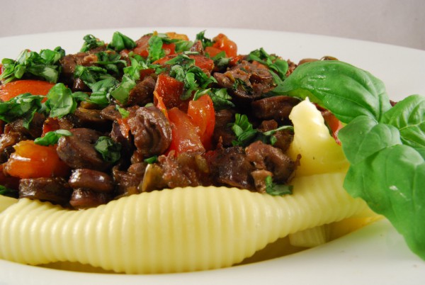 Hähnchenherzen mit Tomaten auf Pasta, mit Basilikum garniert