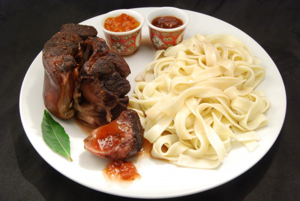 Schweinshaxe-Scheibe mit Dips, Pasta und Rotweinsauce