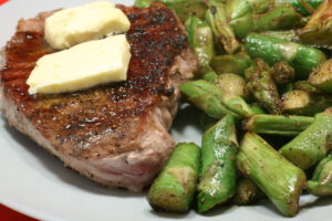 Gegrilltes Schweinenacken-Steak mit Knoblauchbutter und grünem Spargel