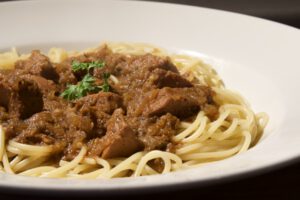 Stierhoden-Gulasch in dunkler Sauce mit Spaghetti